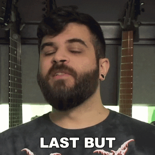 a man with a beard wearing a black shirt that says last but