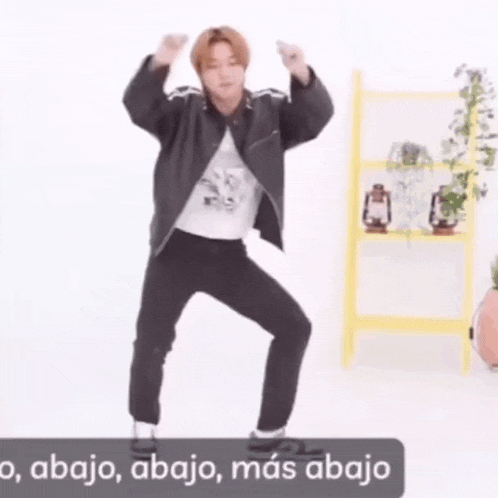 a man in a black jacket and black pants is dancing in front of a yellow ladder