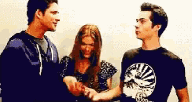 two men and a woman are shaking hands in front of a wall