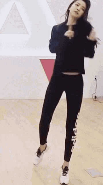 a woman is dancing on a wooden floor in a room with other women .