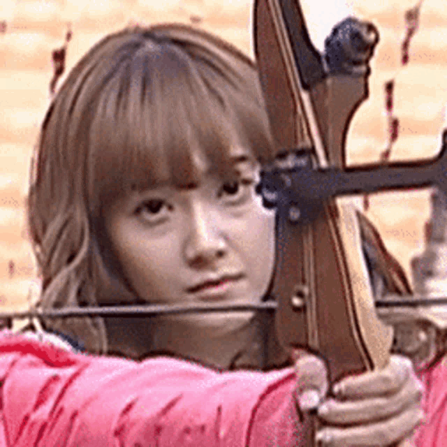 a young woman is holding a bow and arrow in her hand .
