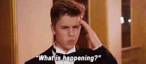 a young man in a tuxedo is scratching his head while asking what is happening .