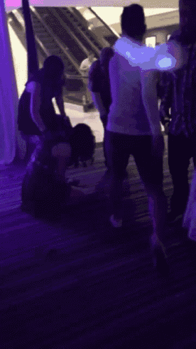 a group of people are standing in a dark room with purple lights behind them