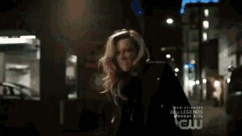 a woman is standing on a city street at night holding a bubble .