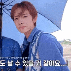 a man in a blue shirt is holding an umbrella .