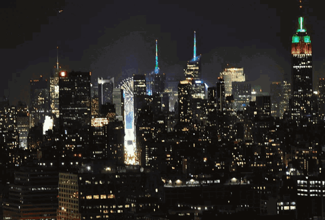 new york city skyline at night with the empire state building lit up