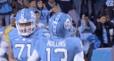 two football players hugging each other in front of a crowd