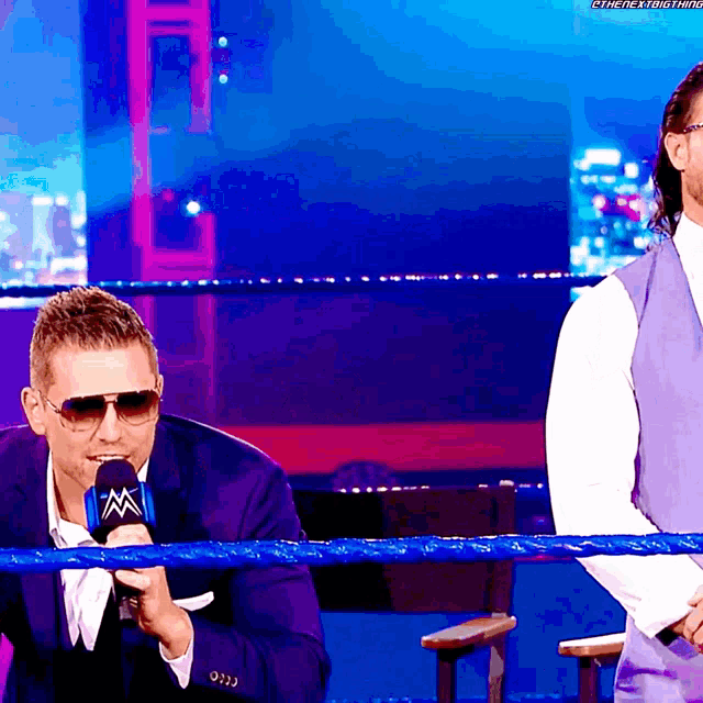 a man in a suit is talking into a microphone that says wwe on it