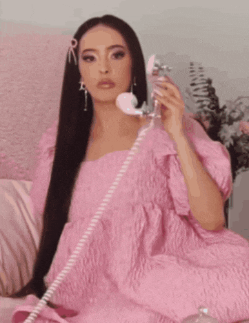 a woman in a pink dress is talking on a pink telephone with the words hello on the bottom