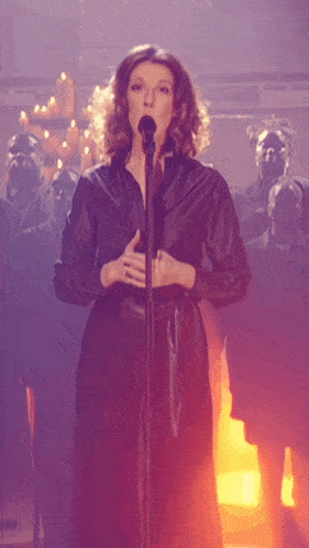 a woman singing into a microphone in front of a crowd