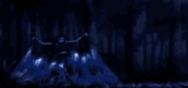 a person is standing in the dark with a blue light coming out of their hands .