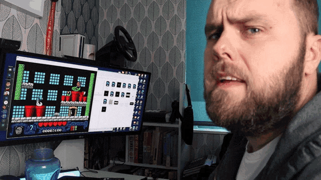 a man sitting in front of a computer monitor with a game on it