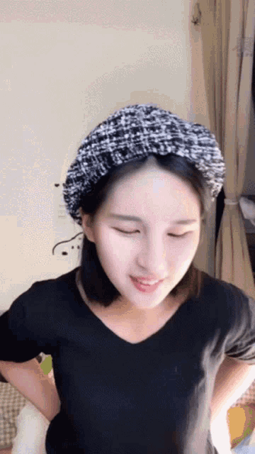 a woman with her eyes closed wearing a black shirt and a black hat