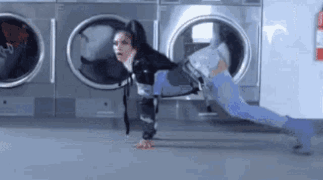 a woman is doing push ups in front of a washing machine