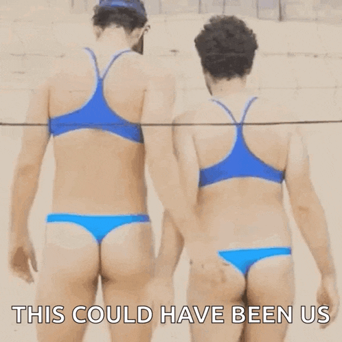 two men in bikinis are standing next to each other on a beach and one of them is touching the other 's butt .