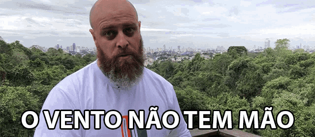 a bald man with a beard stands in front of a city skyline with the words o vento nao tem mao written below him