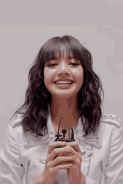 a woman in a white jacket is smiling while holding a microphone .