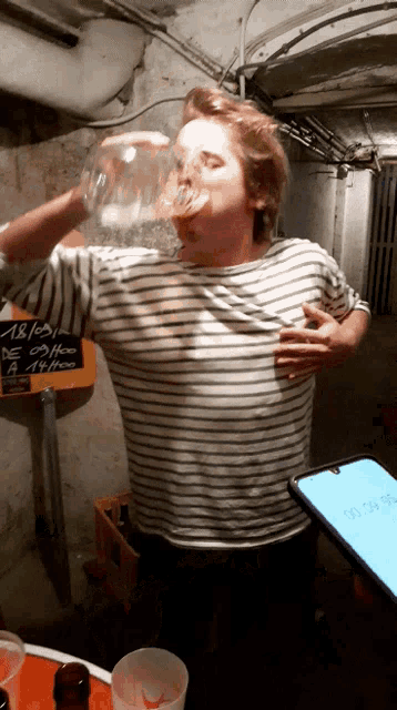 a man drinking from a glass with a chalkboard behind him that says ' de coffee '