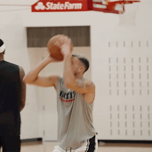 a man holding a basketball in front of a sign for state farm