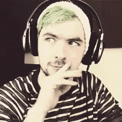 a man with green hair and headphones is wearing a striped shirt .