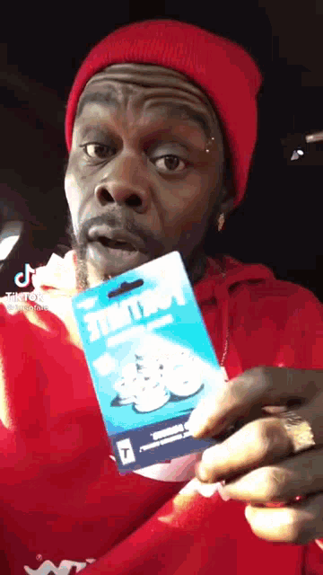 a man in a red hat is holding a gift card that says fortnite
