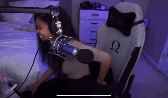 a woman wearing headphones is sitting in a chair with the letter ω on the back