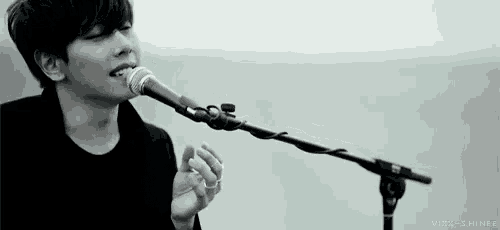 a man is singing into a microphone while standing on a stage .
