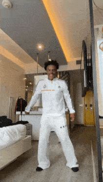 a man in a white adidas jacket is dancing in a room