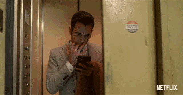 a man in an elevator is looking at his phone with a netflix logo behind him