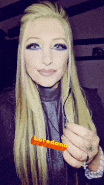 a woman with long blonde hair is holding a piece of paper that says loredana on it