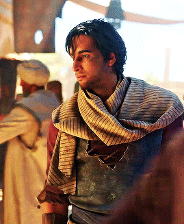 a man wearing a scarf around his neck is standing in a room