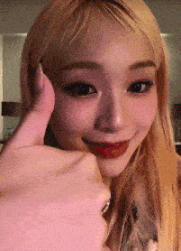 a woman with blonde hair is giving a thumbs up sign