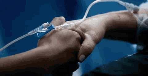 a person holding another person 's hand with an iv in their hand