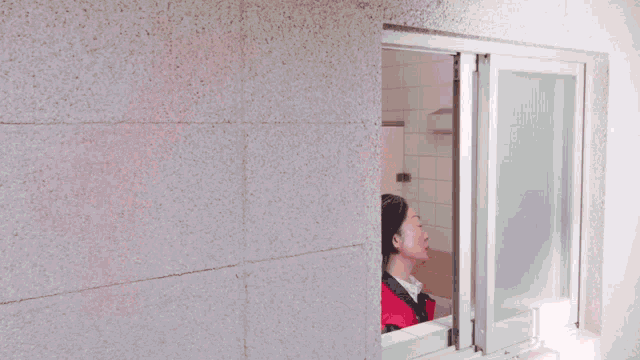 a woman in a red jacket looks out of a window with a red balloon coming out of it