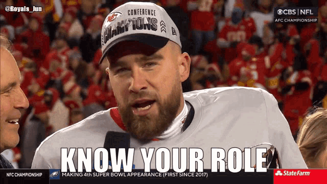 a man with a beard wearing a conference champions hat says " know your role "
