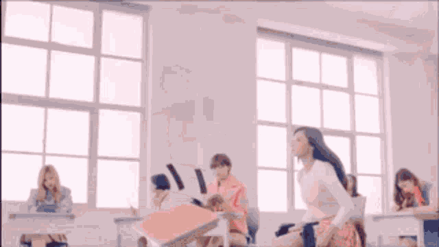 a girl in a pink skirt is standing in a classroom