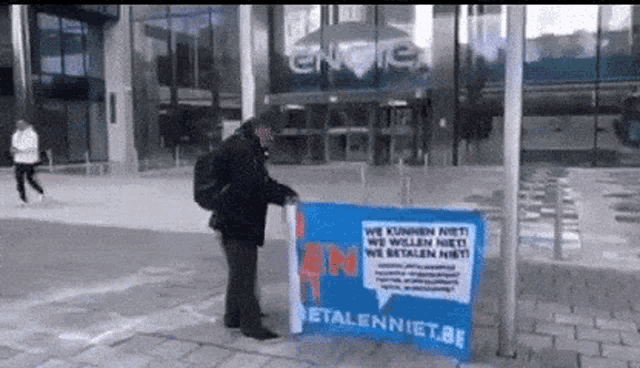 a man holds a sign that says betalenniet.be