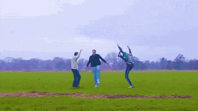 three people are jumping in the air in a grassy field