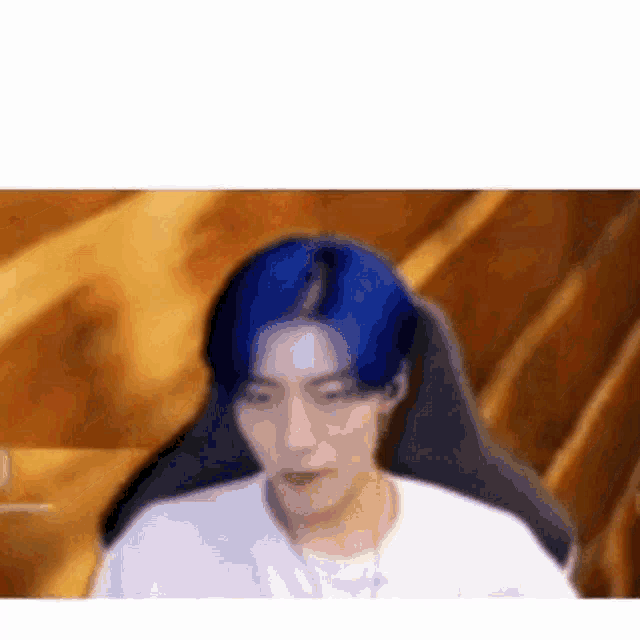 a man with blue hair is sitting in front of a computer screen .