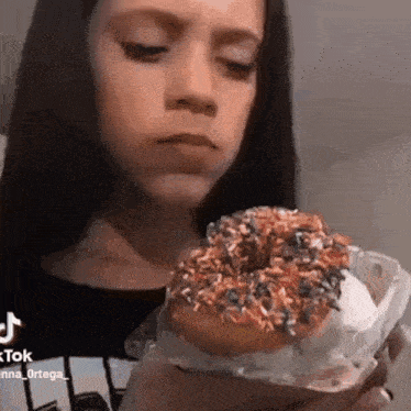 a young girl is holding a donut in her hand .