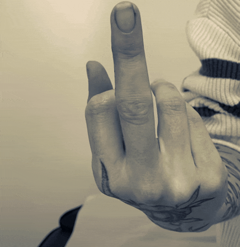 a person 's hand with a tattoo on it is giving the middle finger