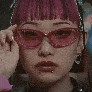 a close up of a woman 's face with pink hair