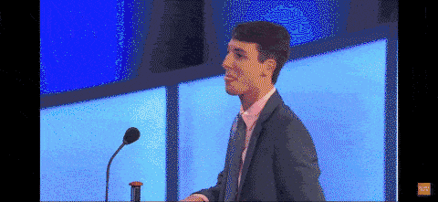 a man in a suit is giving a speech in front of a microphone