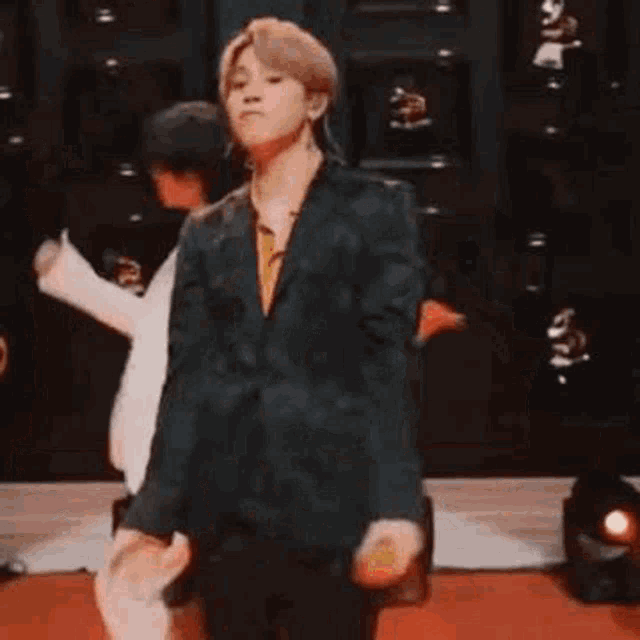 a man in a suit is dancing on a stage in a room .