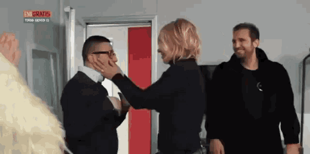 a woman is touching a man 's face in front of a sign that says en gratis