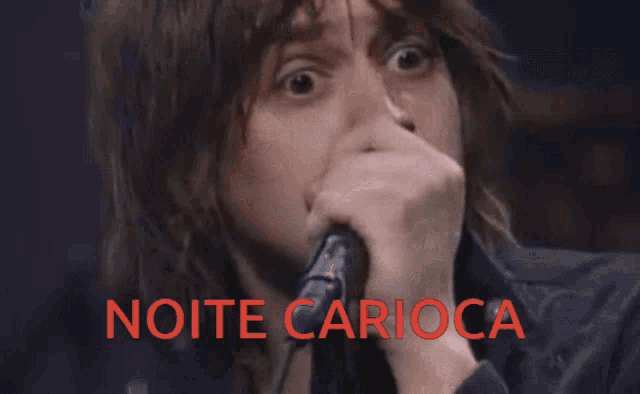 a man singing into a microphone with the words noite carioca written below him