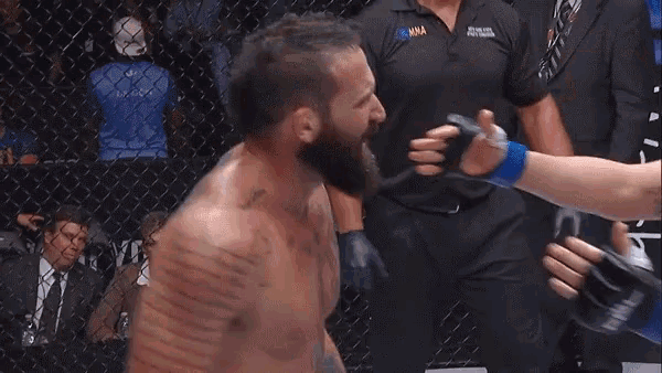 a man with a tattoo on his back is being punched in the face by another man wearing a mma shirt