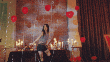 a woman is dancing in a room surrounded by red balloons