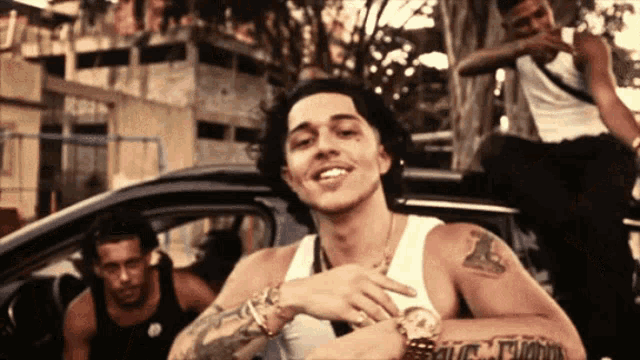 a man in a white tank top has a tattoo on his arm that says ' t.i.c. '