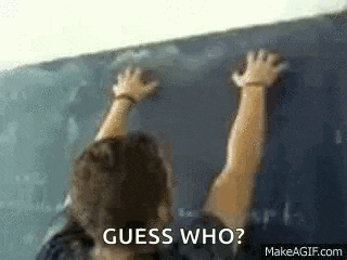 a person is standing in front of a blackboard with their hands up .